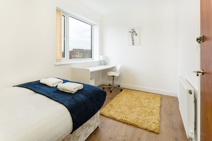 Enjoy a restful night's sleep in our cozy bedroom that doubles as a workspace, complete with a comfortable bed, a desk, and heartwarming decor for a homely feel.