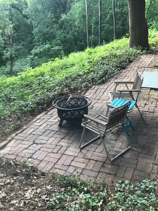 French doors in bedroom lead to outdoor patio with fire pit and wooded view.