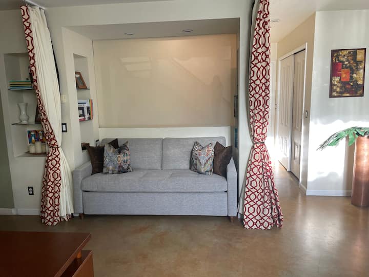 พื้นที่นั่งเล่นชั้นล่างพร้อมลานที่แนบมามีเตียงควีนไซส์ที่สะดวกสบาย 