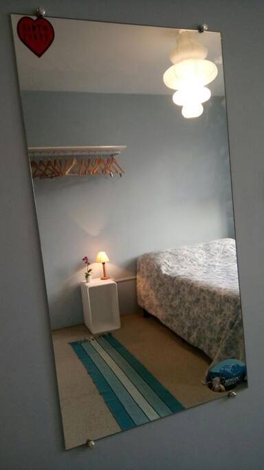 O quarto está completamente mobiliado, tem até espelho e cabides de madeira.