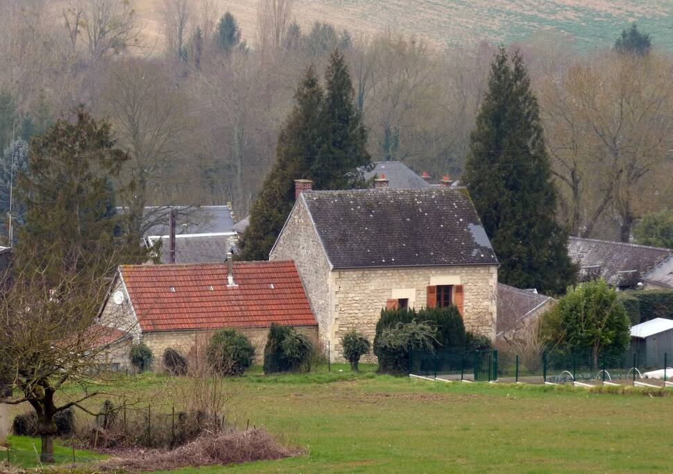 Ma maison vue du champ de derrière, calme assuré. Votre accès est par la porte du bâtiment avec le toit en ardoise.