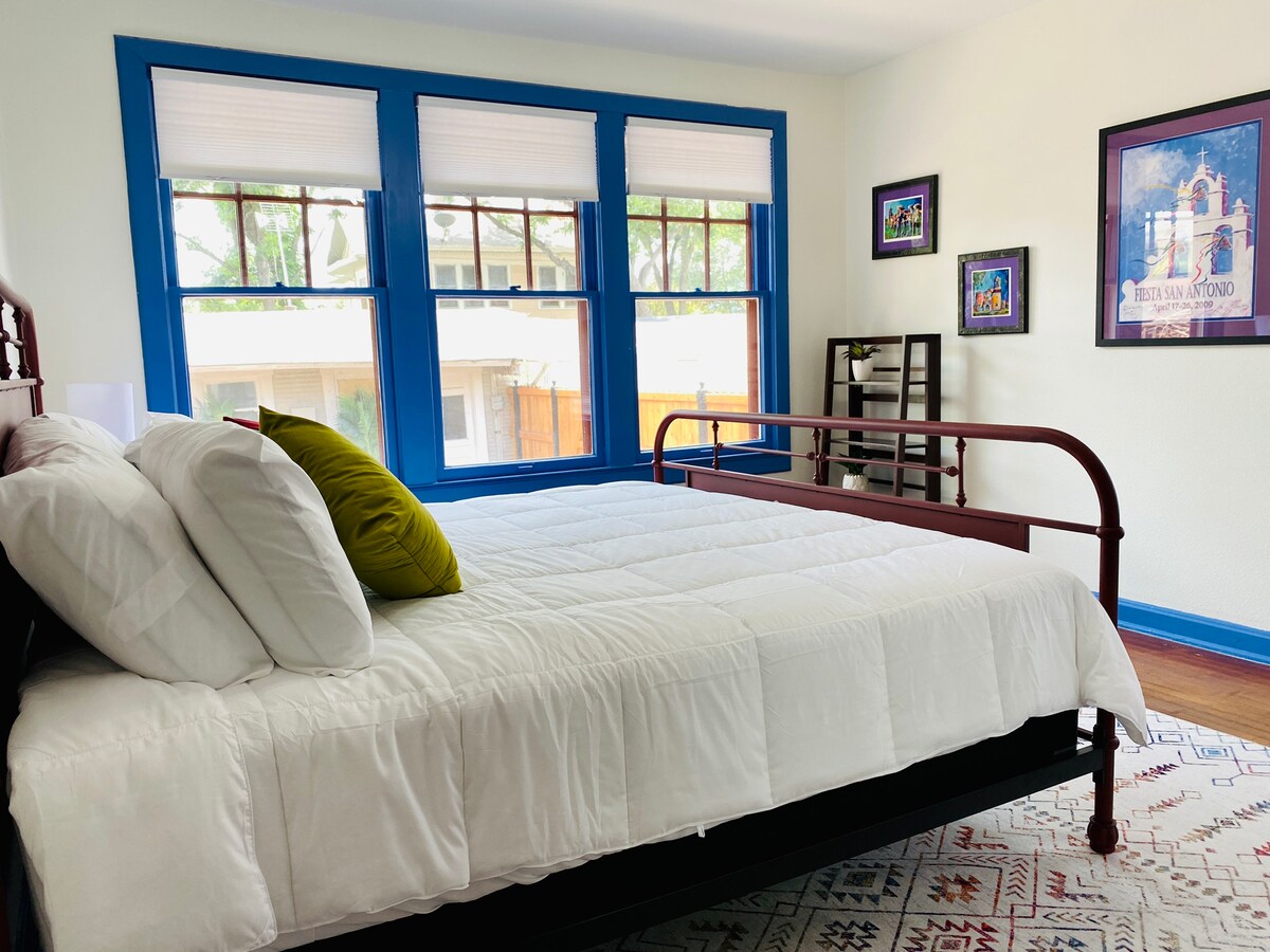 Ძირითად საძინებელში არის კომფორტული საწოლი და კედელზე მიმაგრებული ტელევიზორი. 