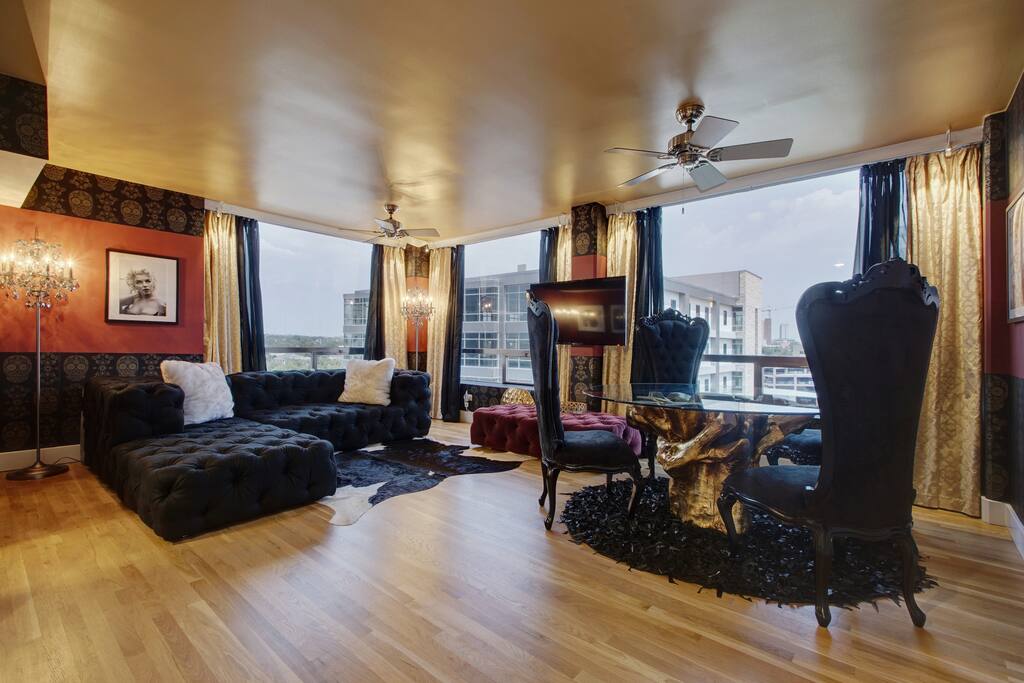 The living room has a lush, dramatic feel with deep red walls, gold and black sugar skull wallpaper