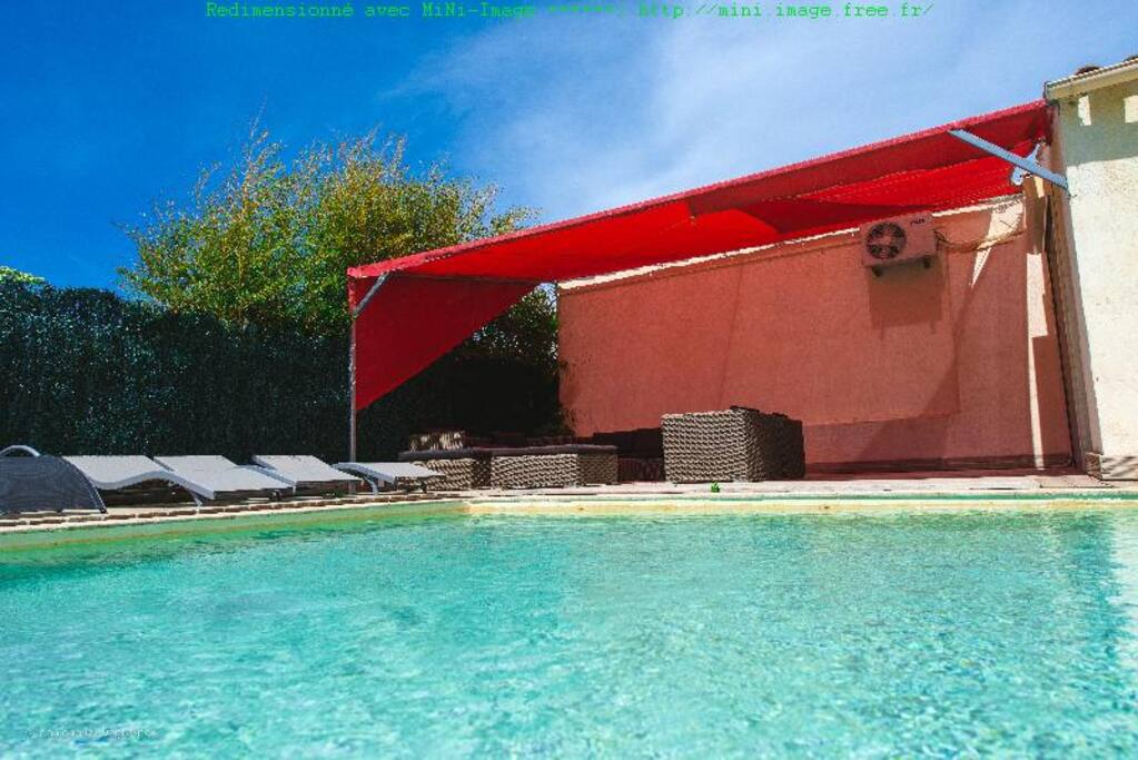 La piscine sécurisée avec transats et salon d'été couvert