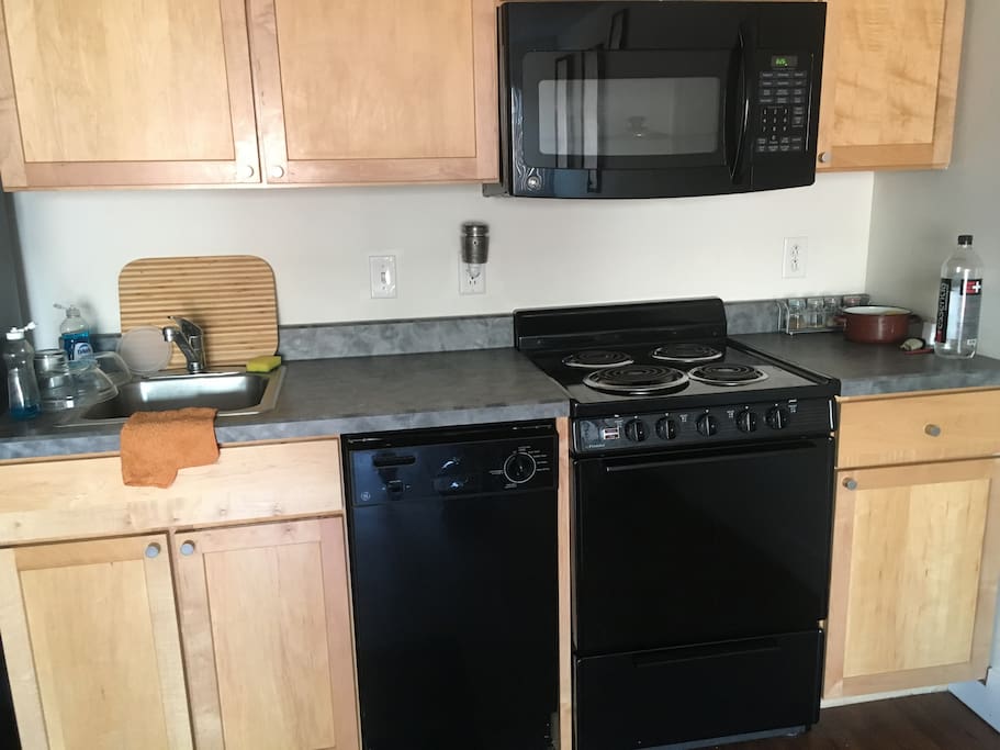 Full kitchen with many amenities including a microwave, dishwasher, dishes, also pots and pans.