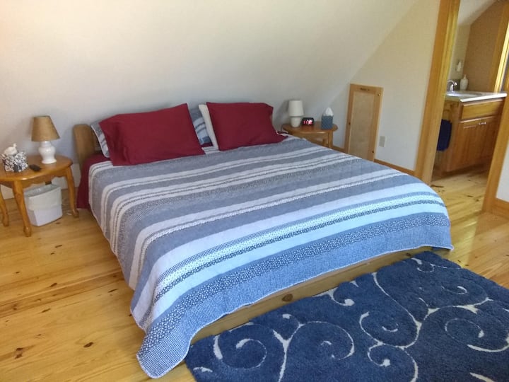 Ზემოთ საძინებელი დიდი საწოლით და მიმდებარე ნახევარი აბაზანით.