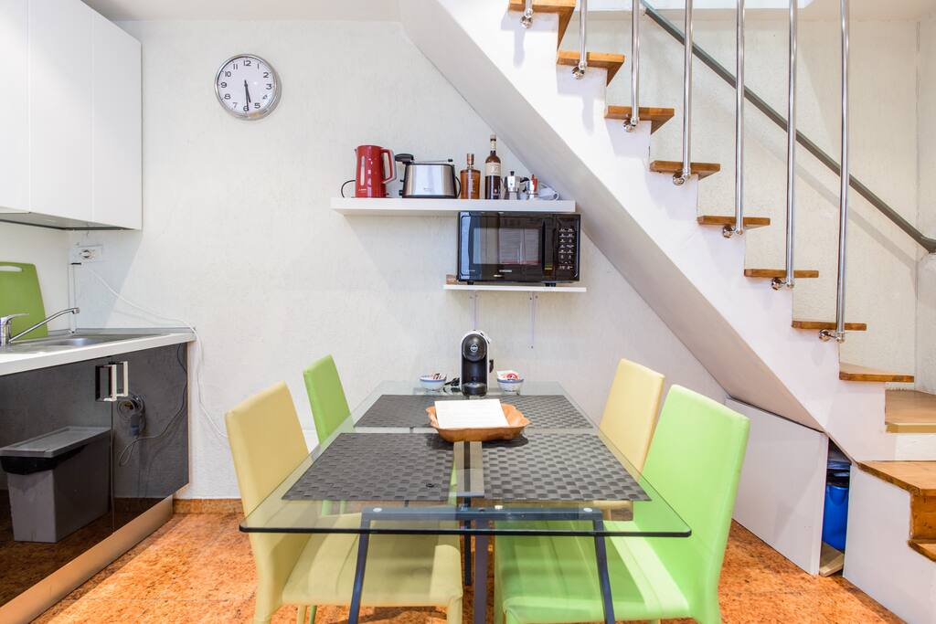 A beautiful view of the dining space (coffe machine is on the table and the other appliances are on the shelves) and the stairs leading to bedroom 1
----
Una bella vista della sala da pranzo (con macchina del caffè sul tavolo e gli altri elettrodomestici sulle mensole) e delle scale per la camera da letto 1
