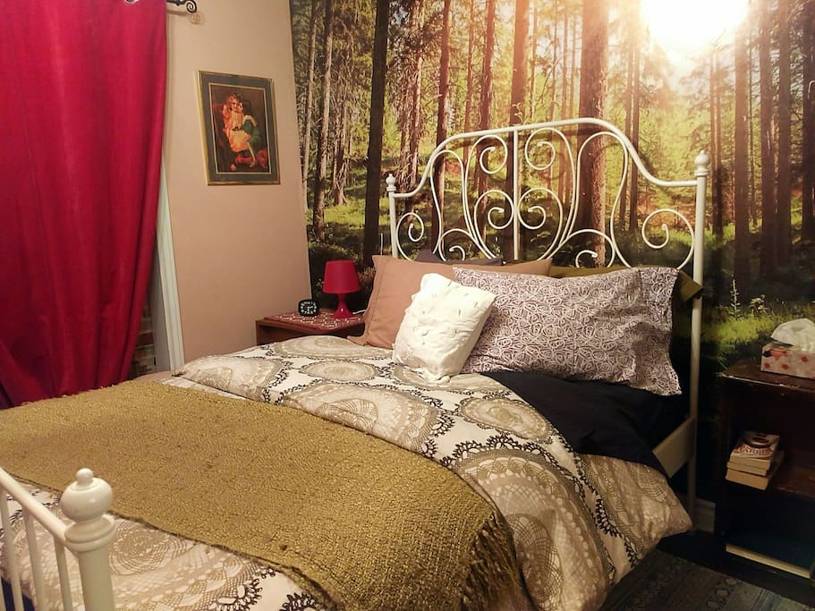This brand new double bed is made up with a duvet, four pillows (of varying firmness) and fresh linens in fun colours set in front of a photo mural of an old growth forest.