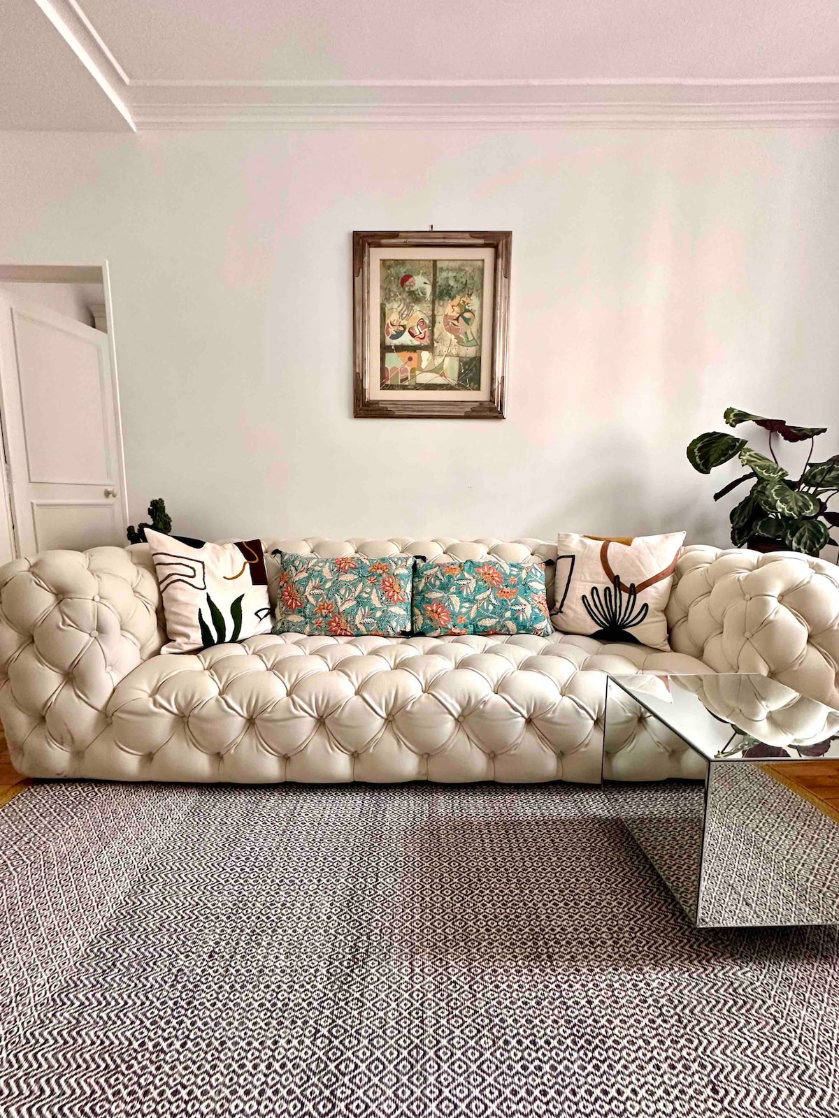 غرفة معيشة مع أريكة بتصميم وطاولة قهوة وسجادة بجوار متجر كونران - تُظهر اللوحة كرنفال البندقية 