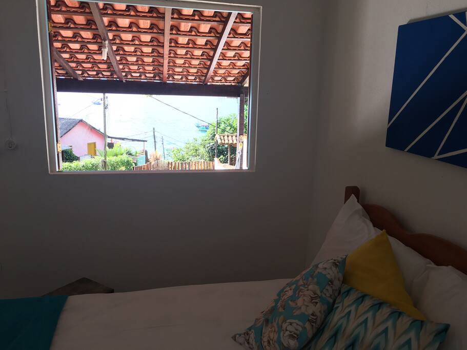 Primeiro quarto com vista para o mar, com duas camas sendo uma casal e uma solteiro.