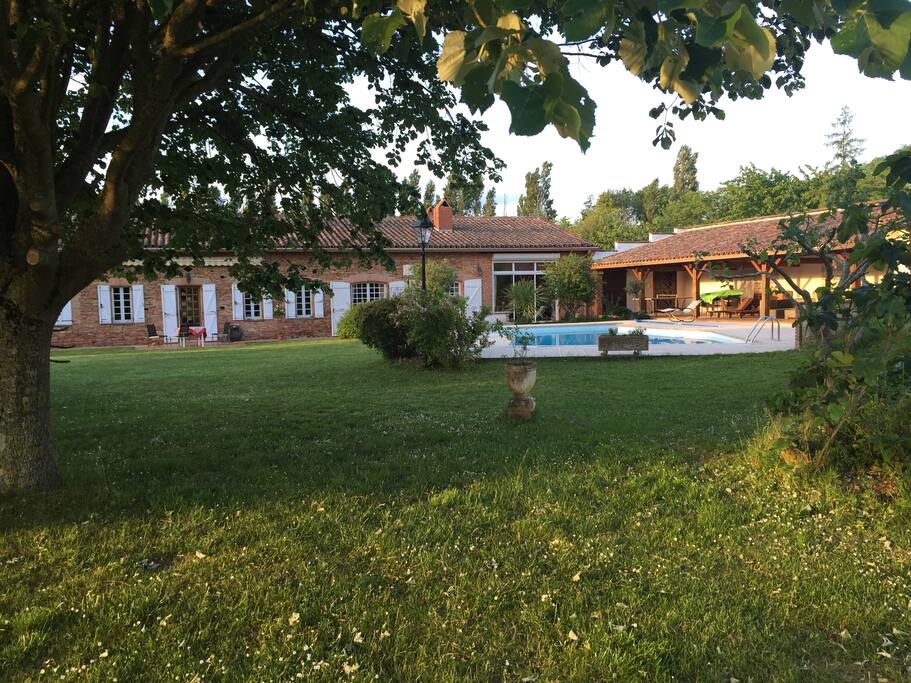 La propriété, sa terrasse couverte, sa piscine et ses arbres