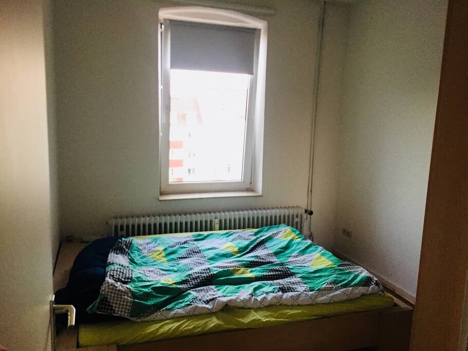 Schlafzimmer mit großem Bett und Fenster zum Innenhof