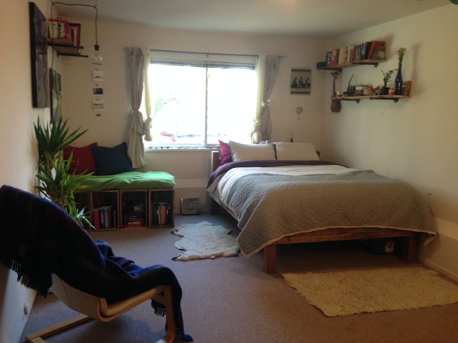 Room with queen bed, poang chair and bench.