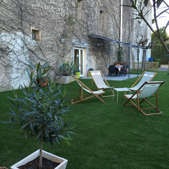 Agréable jardin privatif avec terrasse sous pergola et table pour déjeuner. Barbecue et plancha à disposition