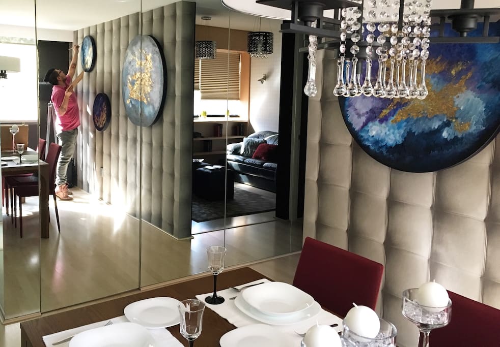Vista a la sala de TV desde el comedor a través del muro de espejos. El departamento cuenta con losa para 8 personas y juego de vasos, copas y cubiertos para el mismo número de comensales.