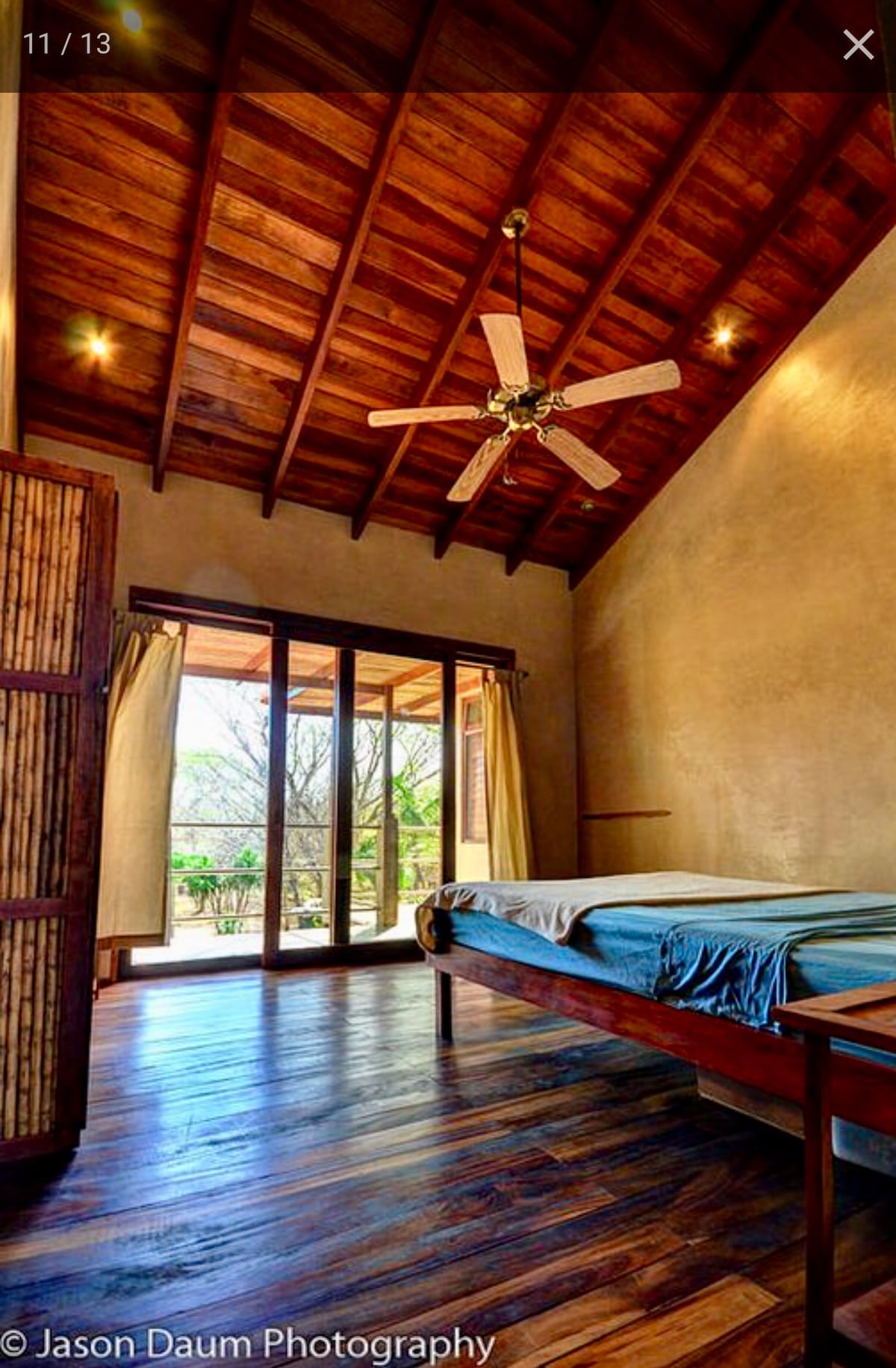 Chambre avec un plancher de bois dur et un plafond, porte coulissante vers le balcon