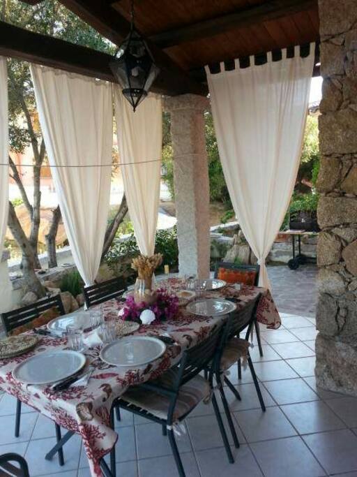 Il bellissimo patio con il tavolo apparecchiato e le tende bianche