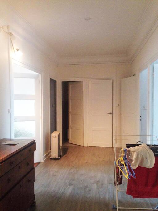 l'entrée spacieuse de l'appartement qui dessert (de gauche à droite) une première chambre, le salon, une seconde chambre, les toilettes, la salle de bains, une troisième chambre et enfin la cuisine