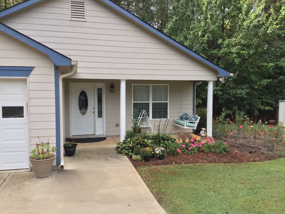 An inviting front porch and swing beside a rose garden