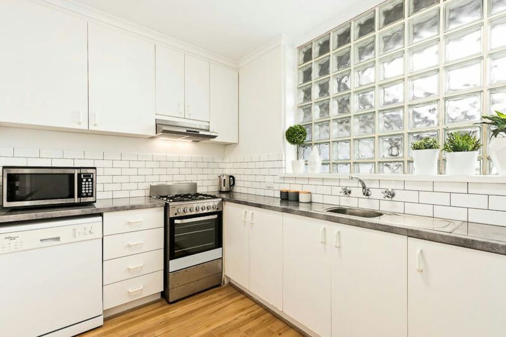 Bright, fully equipped kitchen with microwave, dishwasher, oven, stove and fridge.