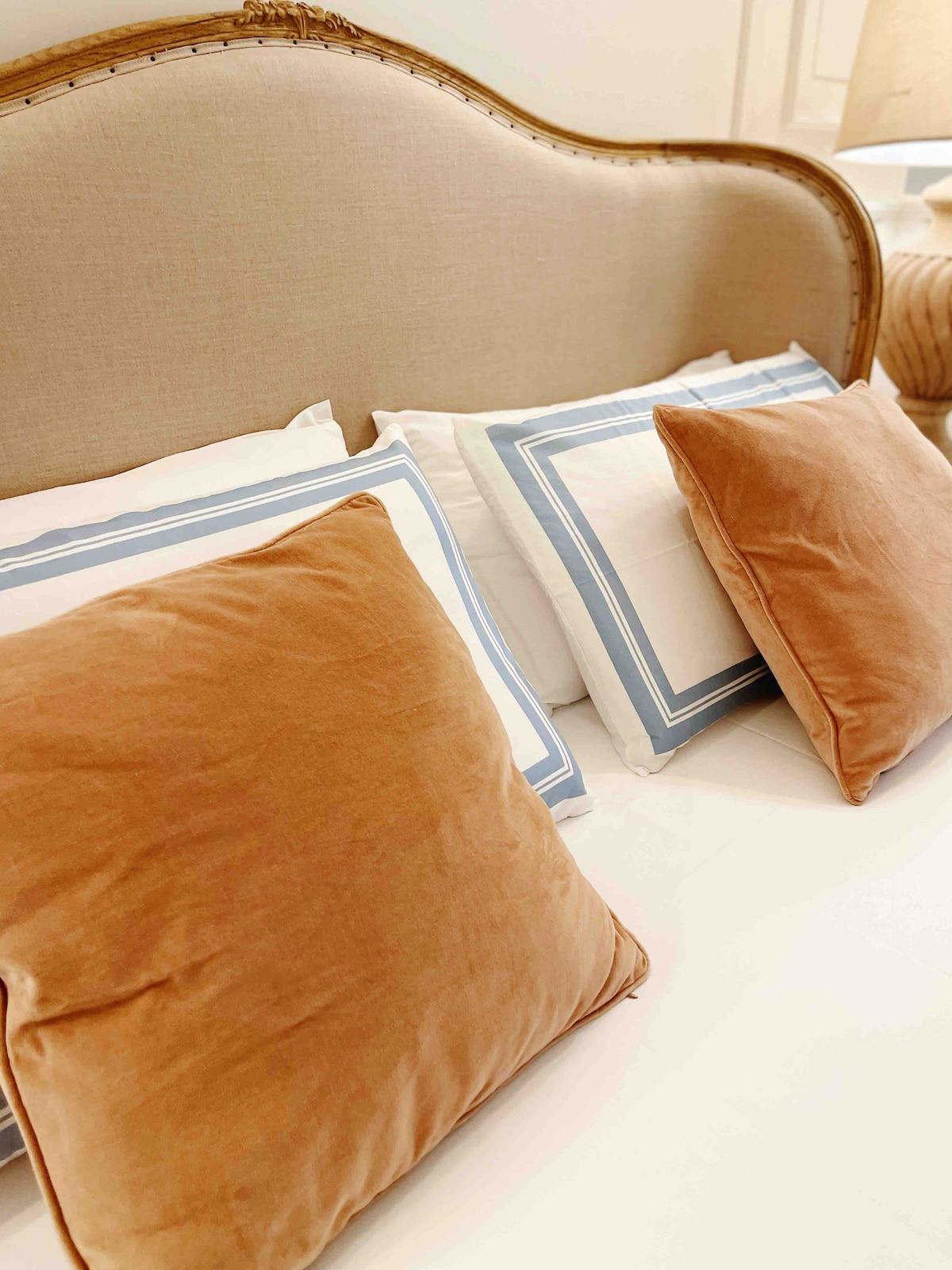 A cozy bed is highlighted by soft, rectangular pillows positioned against a neutral headboard. The linens are complemented by decorative throws featuring a subtle blue pattern, adding a touch of elegance to the inviting space.