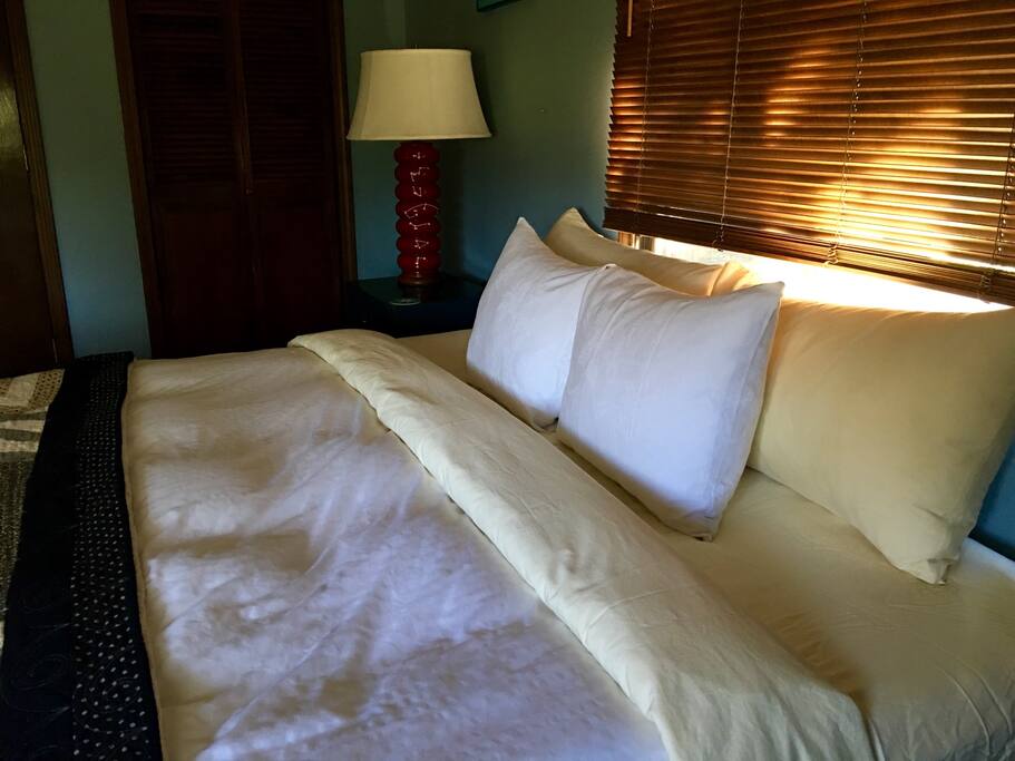 King bed with cotton sheets, down comforter, quilt.