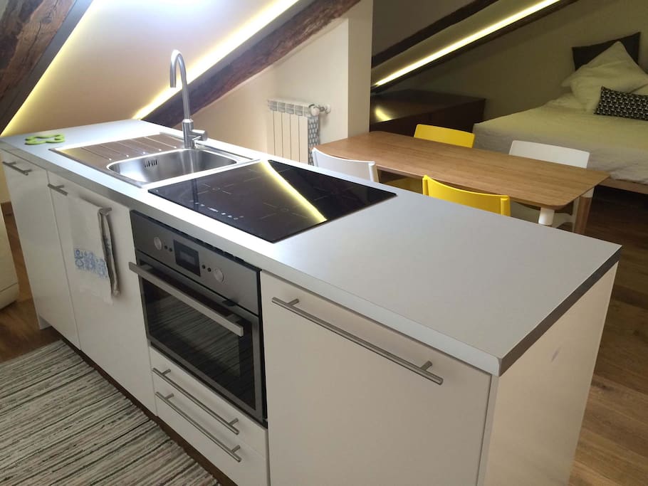 Cucina con piano a induzione, forno, microonde, lavastoviglie e frigo.
