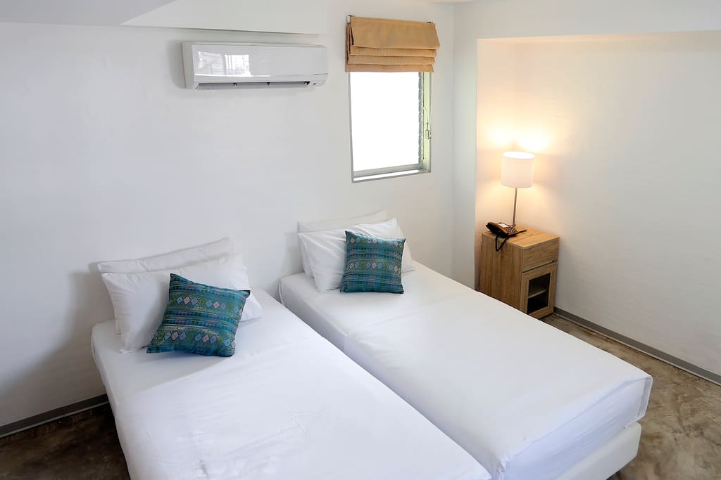 Lamp on a side of the bed with two single-sized mattresses in secondary bedroom