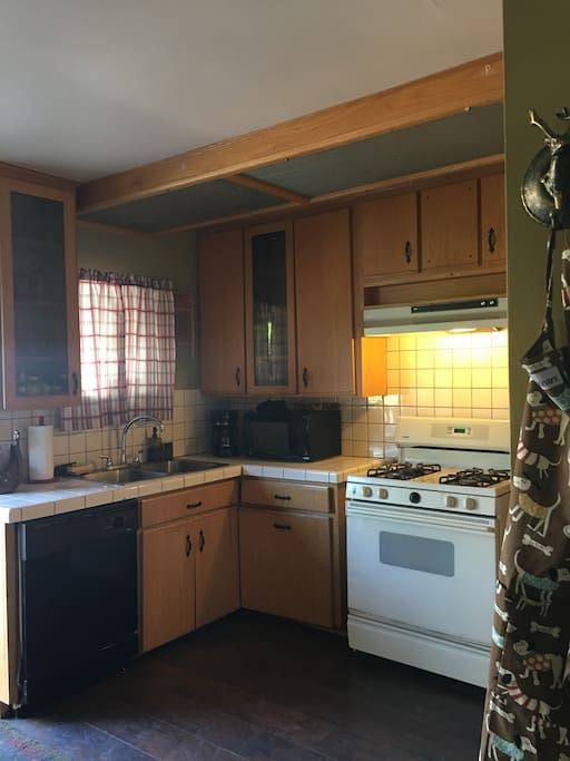 Fully stocked kitchen with fridge, appliances, coffee maker and utensils and dishes and cookware