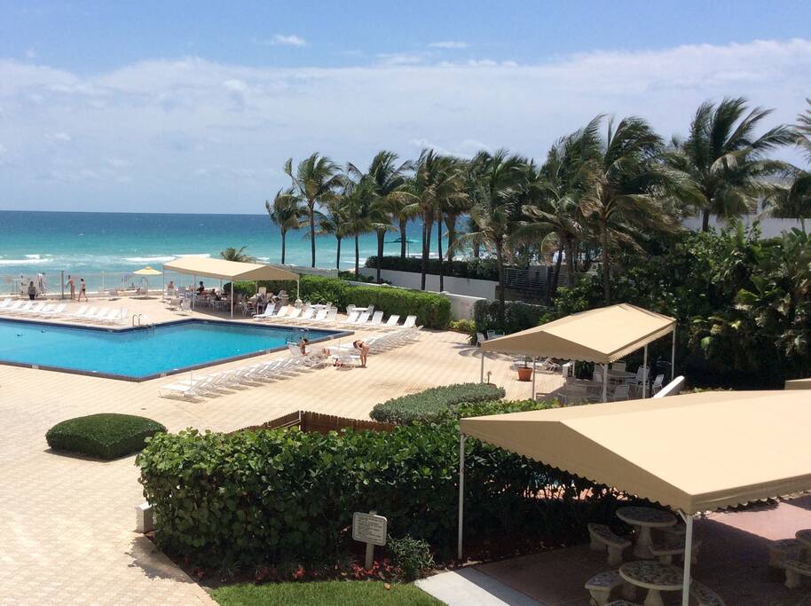 The view from the balcony - very large pool, BBQ area, Jacuzzi, tables, beach chairs, towels, etc.