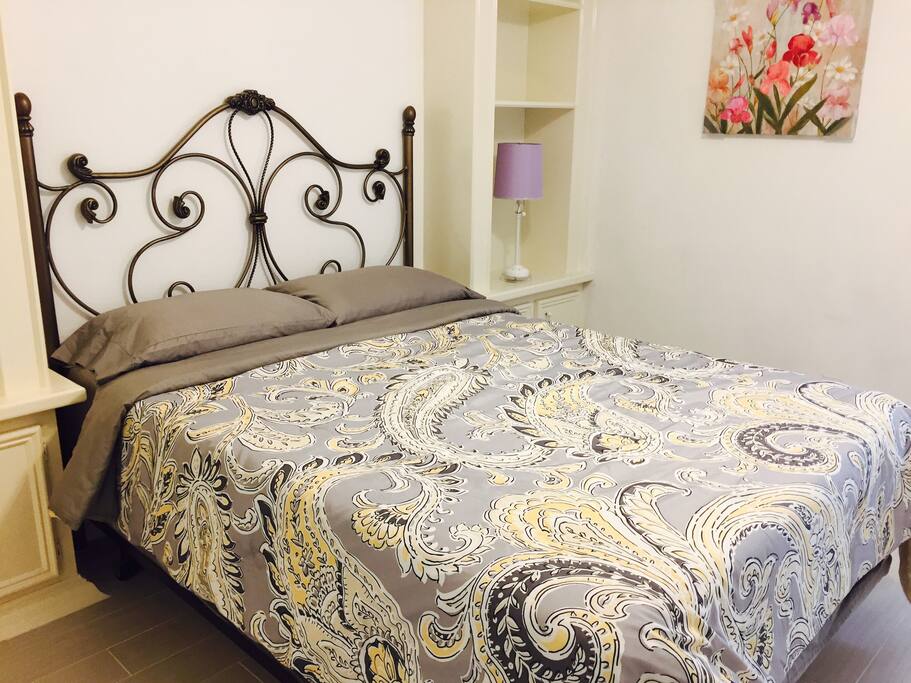 A queen size bed and a writing desk in the bedroom.