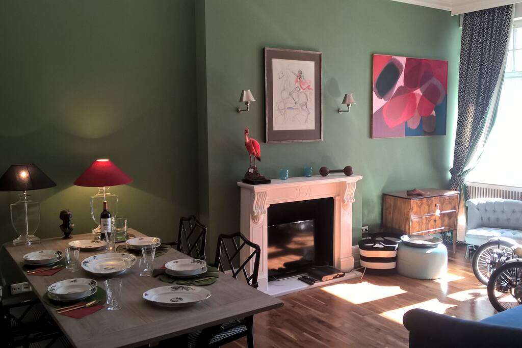 A bright british green Sitting and dining room. The TV is hidden in the fire place.