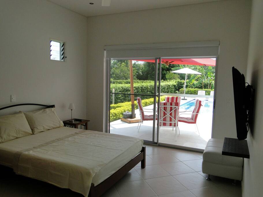 Alcoba principal con televisor y terrraza con vista a la piscina