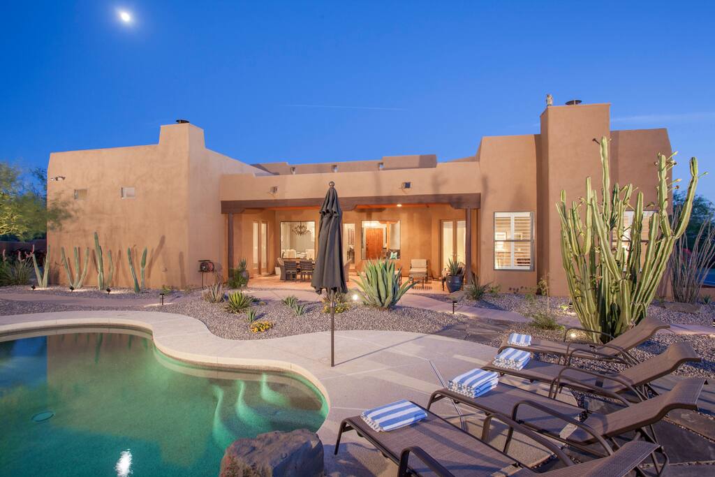 Heated swimming pool has waterfall and connected spa, patio includes gas firepit, gas BBQ, plenty of lounge seating and a dining table for eight