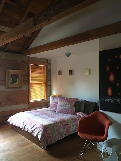 Main sleeping area surrounded in original exposed heart of pine shiplap from 1920 and vaulted beamed ceiling