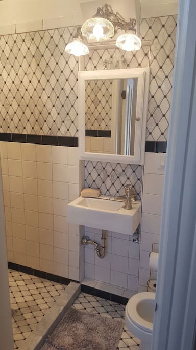Enjoy a hot shower in this Art Deco argyle-tiled bathroom next to your room.