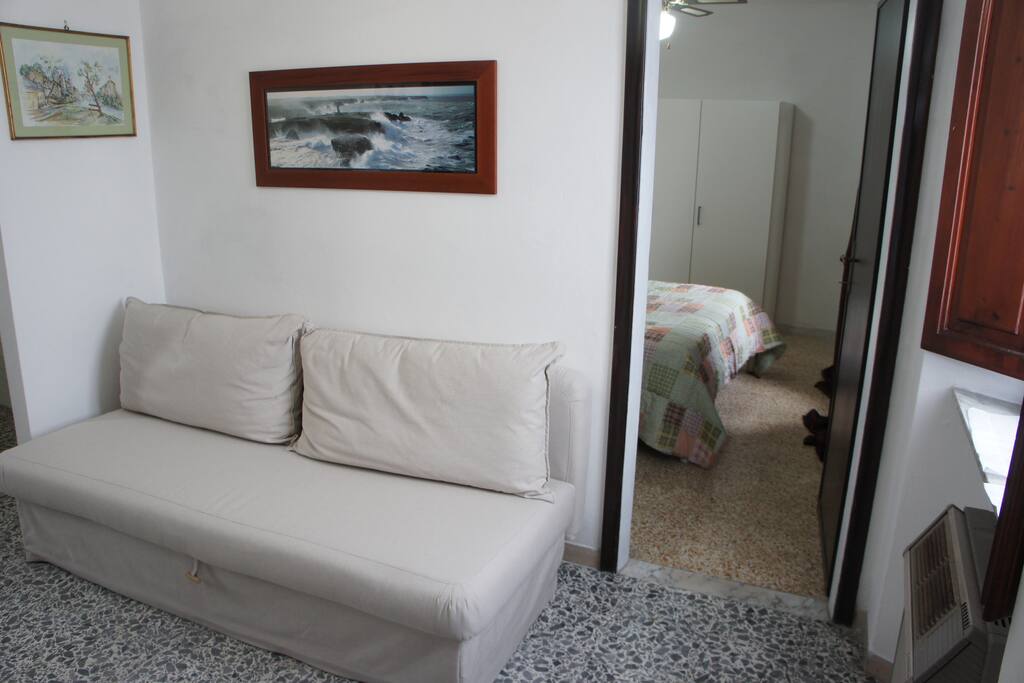 Soggiorno con tavolinetto divano letto matrimoniale ingresso e finestra.