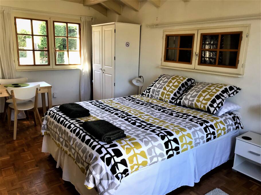 Double bedroom with wardrobe, chest of drawers, TV with integral DVD player, small extendable table and chairs.