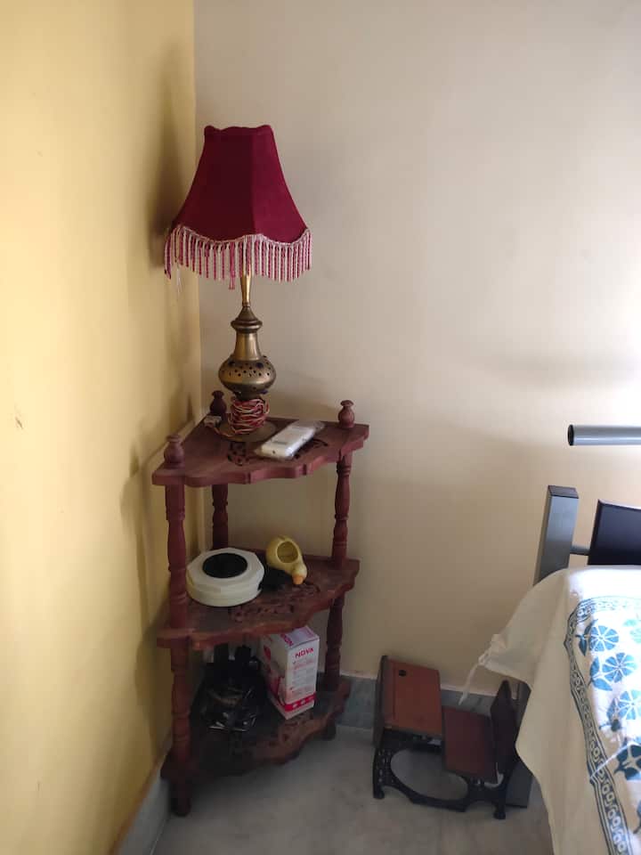 Kona ya huduma kando ya kitanda iliyo na pasi, kikausha nywele,kamba ya kupanua n.k., iliyo na taa ya meza kando ya kitanda.