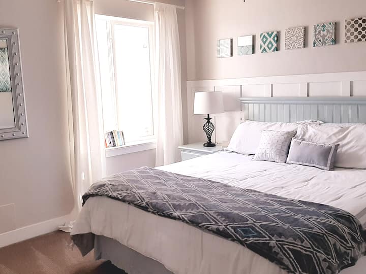 Hauptschlafzimmer mit freundlichem Bett, Doppel-Nachttischen, Celing-Ventilator, Spiegel, Schrank und Wecker. Beide Lampen haben USB-Ladeanschlüsse eingebaut.