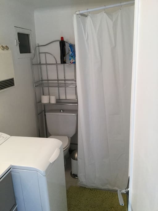 Salle de bain avec une douche, un WC, un lave linge et un lavabo