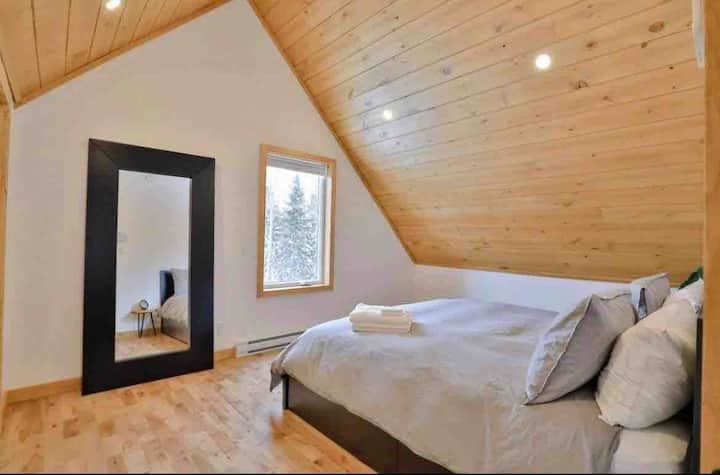 A charming room with a comfortable queen-size bed, where the wooden walls and ceiling create a warm and natural atmosphere.