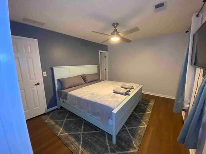Primary suite, king bed with private en-suite bathroom, mounted TV, ceiling fan, and abundant natural light, the most relaxing room in the house.