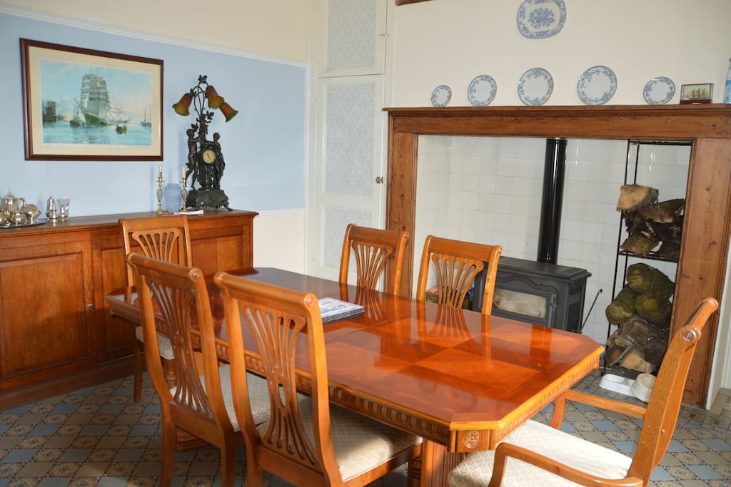 Family dining room with log burner and piano.