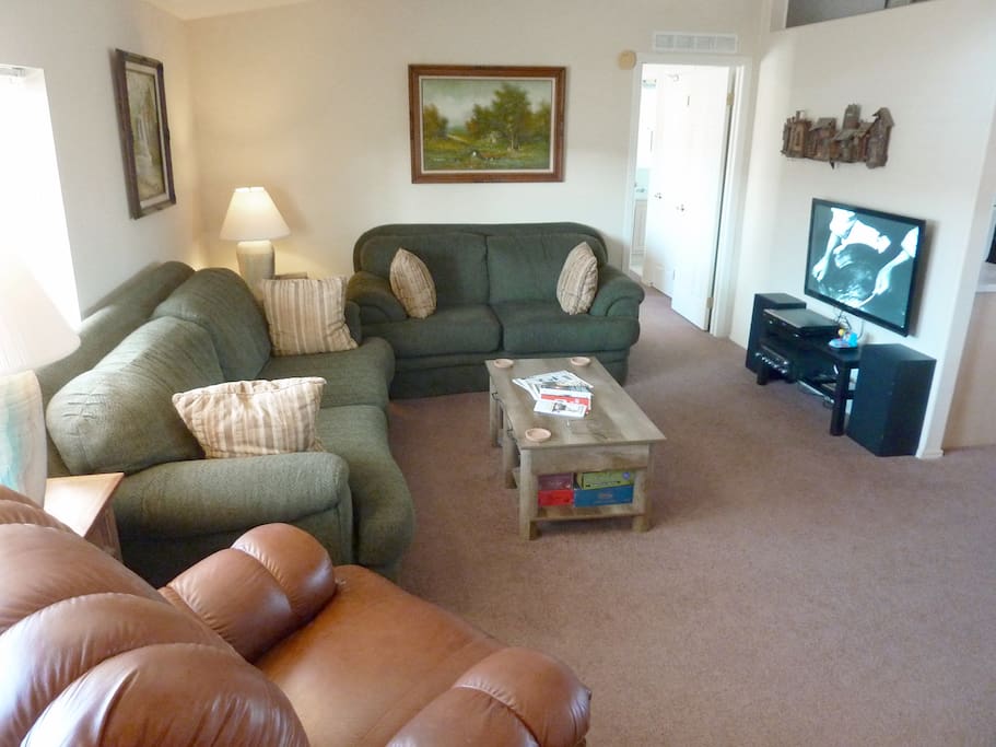 Living room with easy chair, couch, loveseat, TV, DVD player, kid's games, adult games