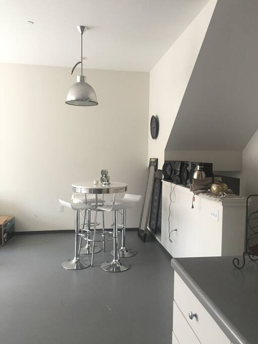 This is the dining space. It is a medium sized table with high bar stools.