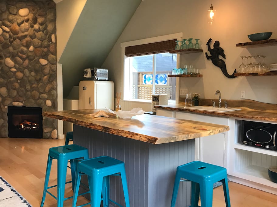 A view of the kitchenette, island and stone fireplace on the main floor of The Carriage House.