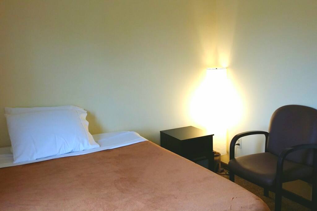 Queen Airmatress, nightstand, lamp and chair in room