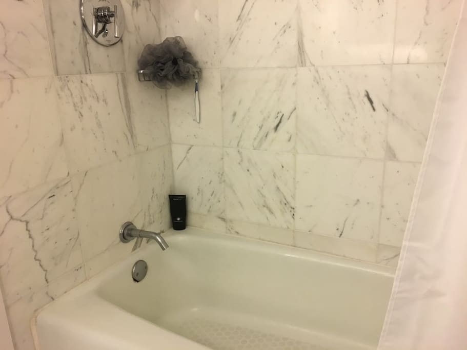New bathtub with marble tiles.