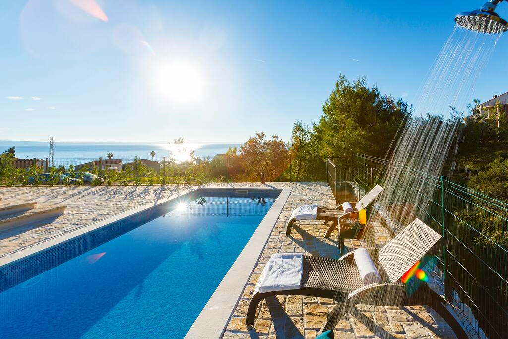 Outdoor shower and sun loungers next to the pool